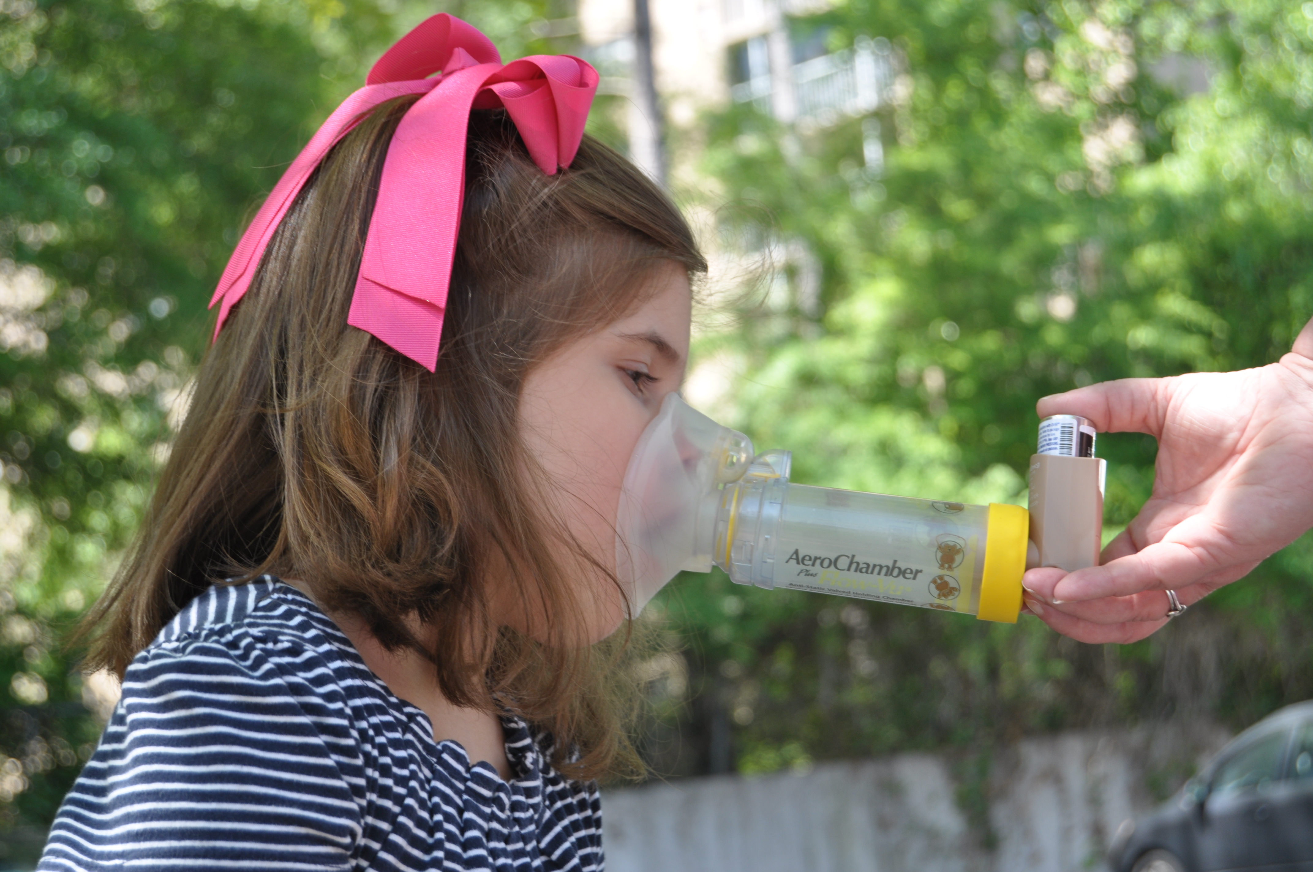 Image of young girl being given asthma medicine via an inhaler and asthma spacer. Image of young girl being given asthma medicine via an inhaler and asthma spacer.
