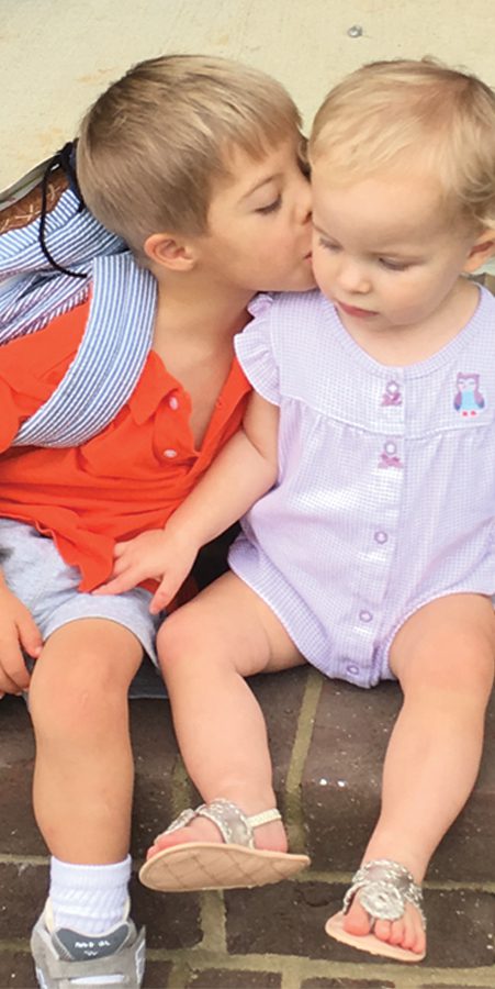 young boy kisses his baby sister goodbye on the way to school