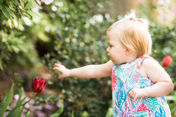 young girl reaches for a flower