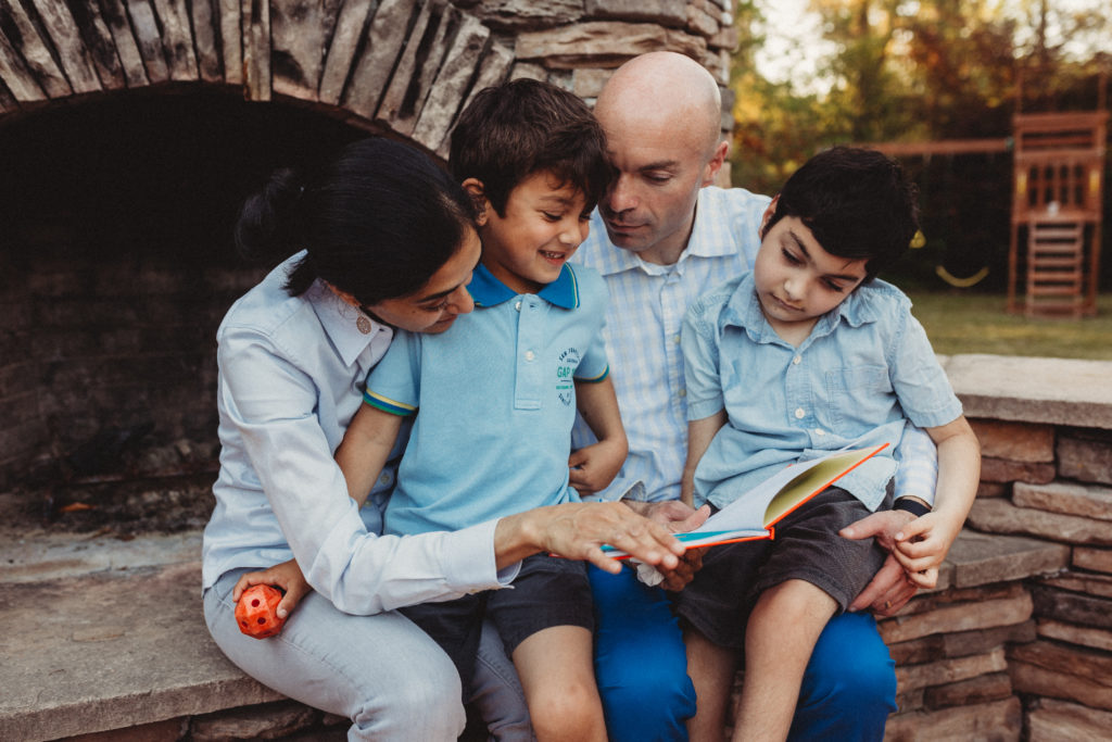 padres y dos niños afuera leyendo