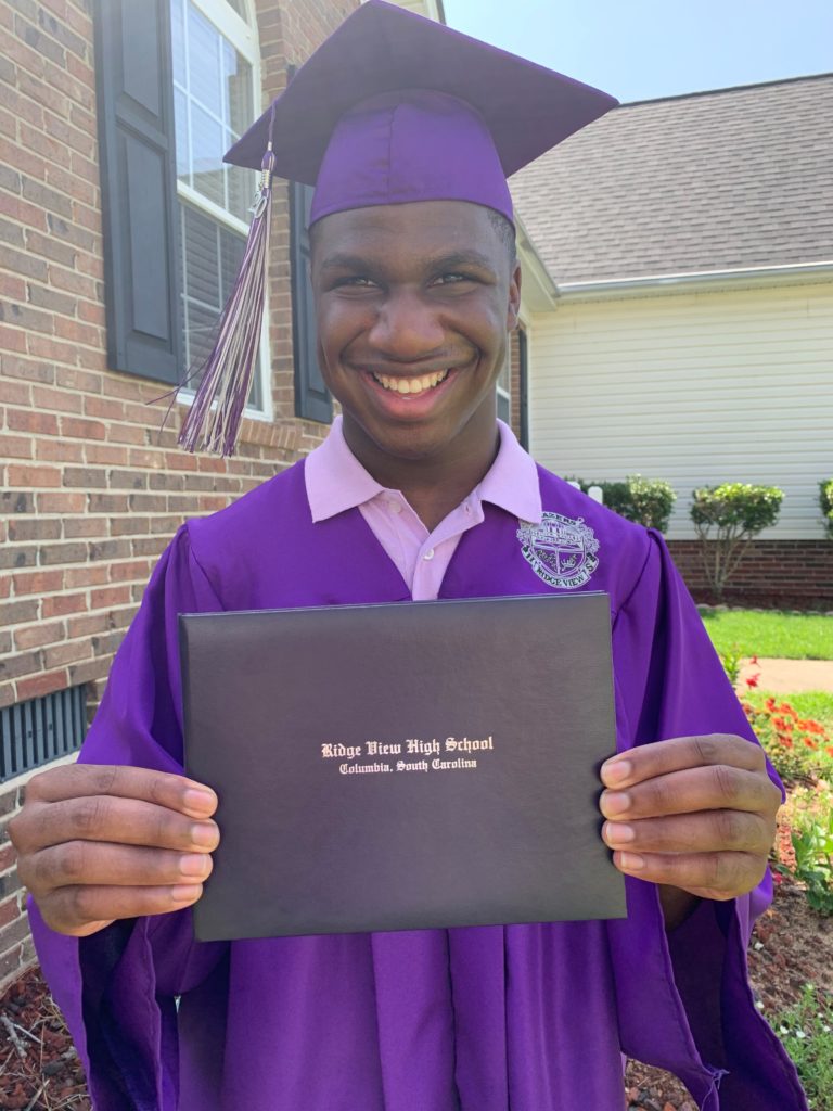 teenage holding certificate in cap and gown