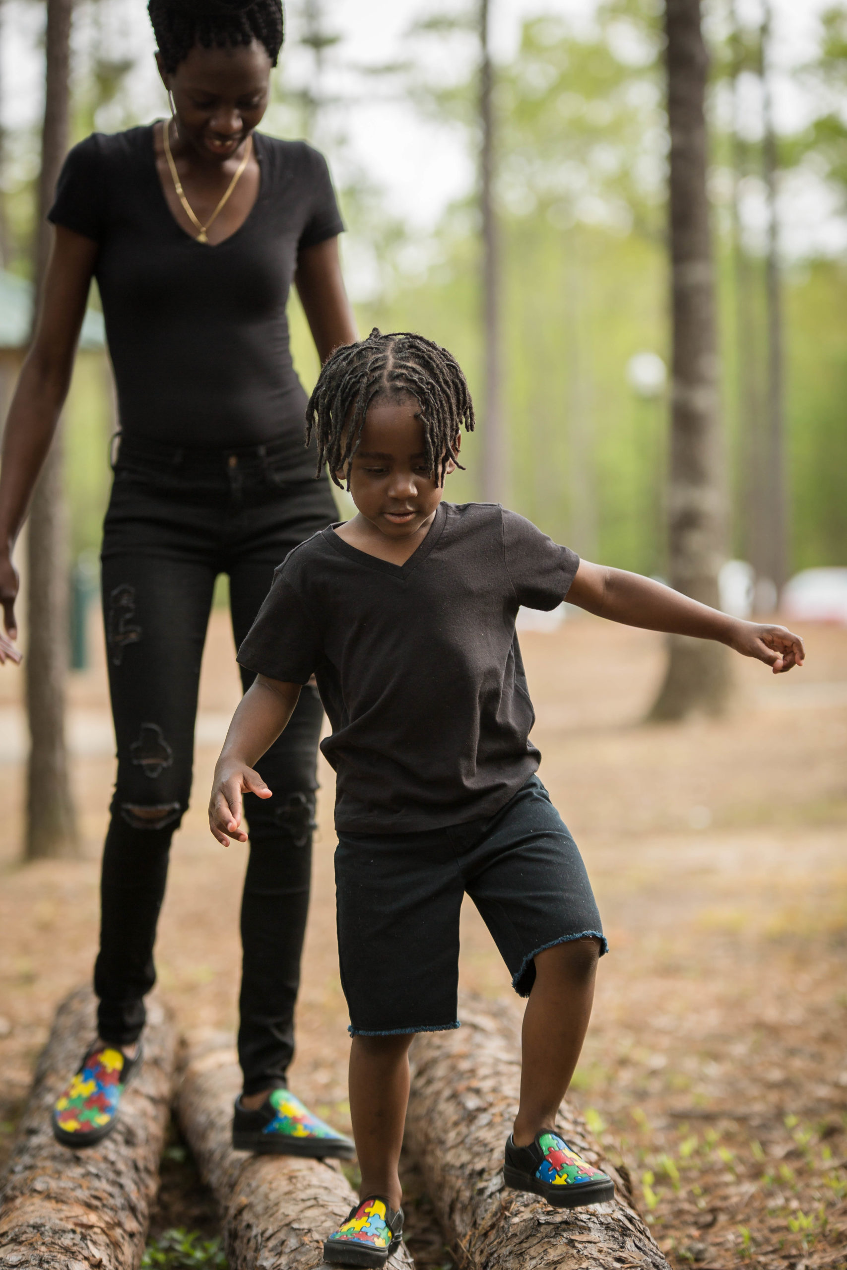 child and woman walk on a log