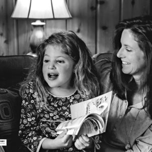 woman and girl sitting on couch with book