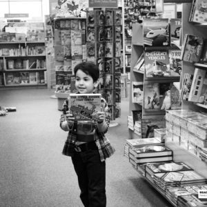boy standing in book store holding a book