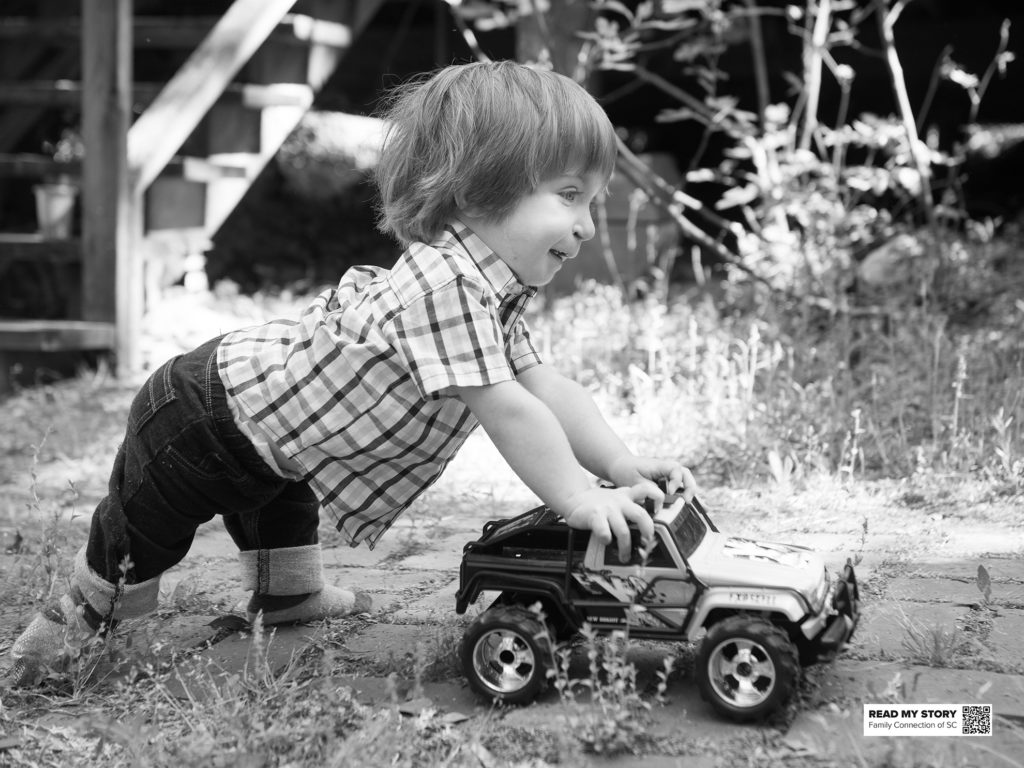little boy pushing a toy truck outside