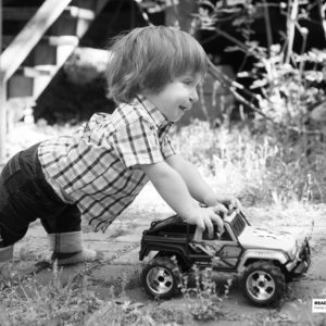 little boy pushing a toy truck outside