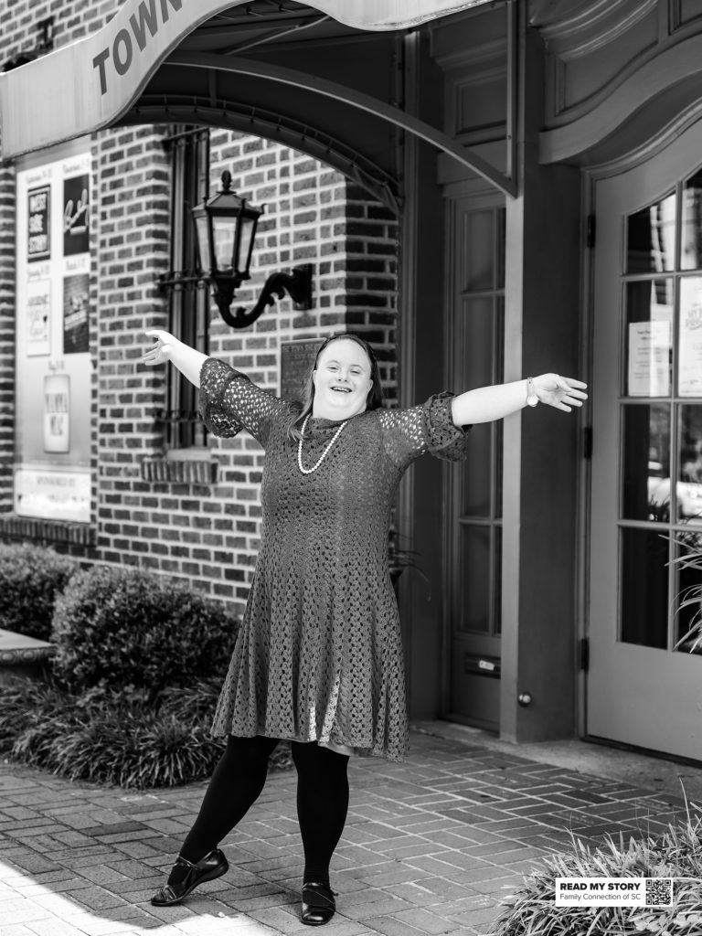 woman outside with arms raised smiling