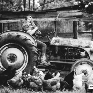 girl sitting on tractor with chickens