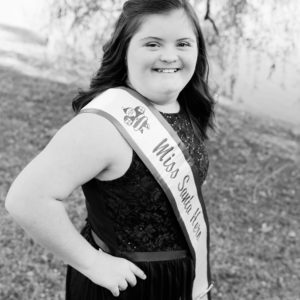 girl in miss santa hero pageant sash and tiara