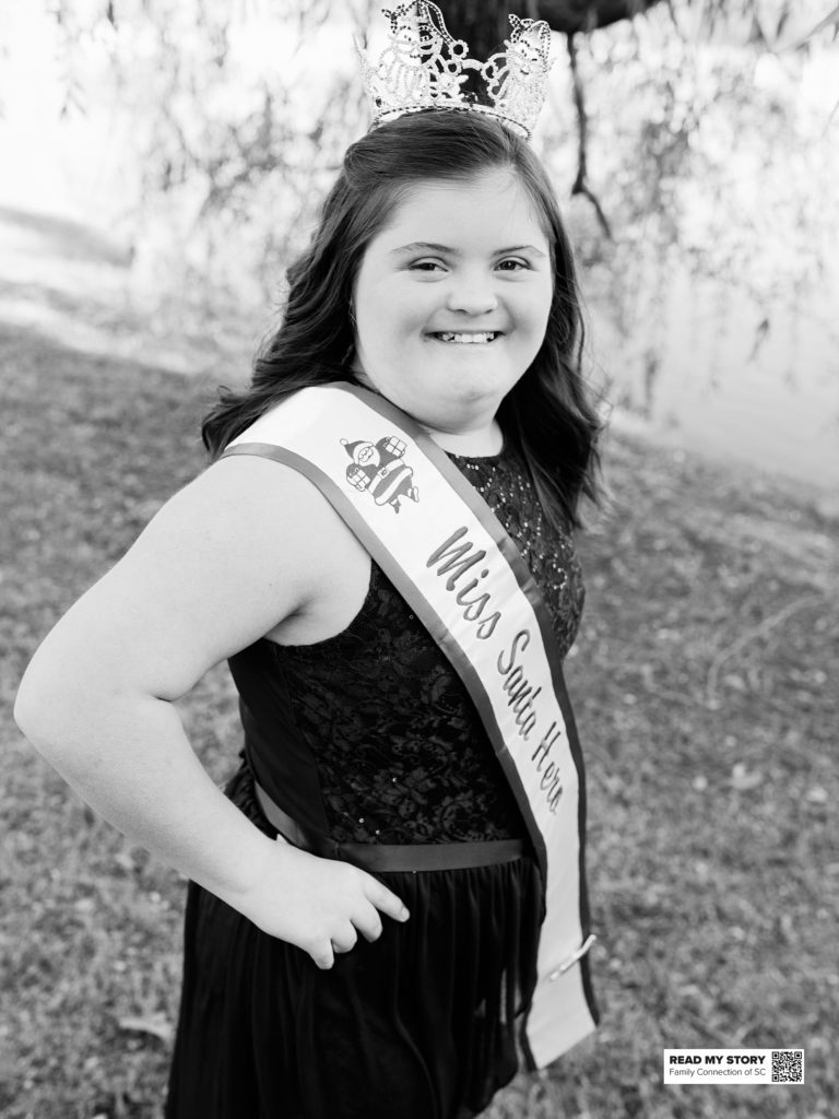 girl in miss santa hero pageant sash and tiara