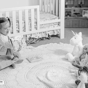 little girl on blanket reading to stuffed animals