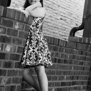 girl leans on a brick wall