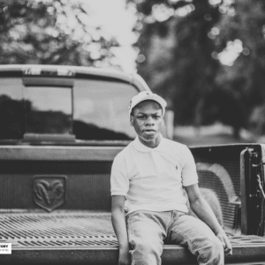 young man sits on the back of a pickup truck