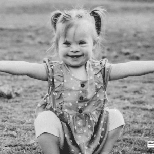 a girl sits in the grass with open arms