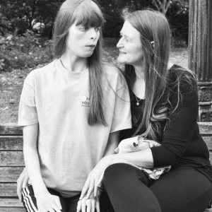 mother and daughter sit on a park bench