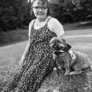 young woman sits on a rock with her dog