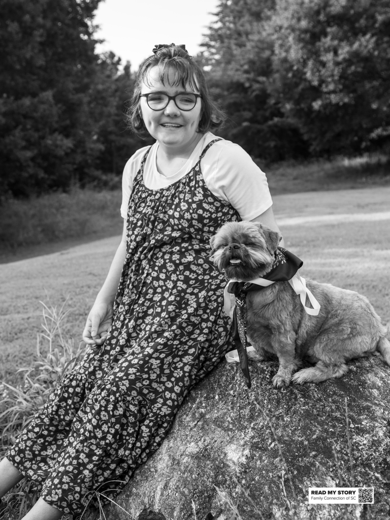 young woman sits on a rock with her dog