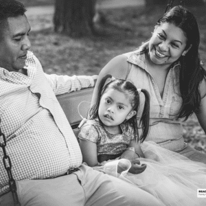 young girl sits in a swing with her family