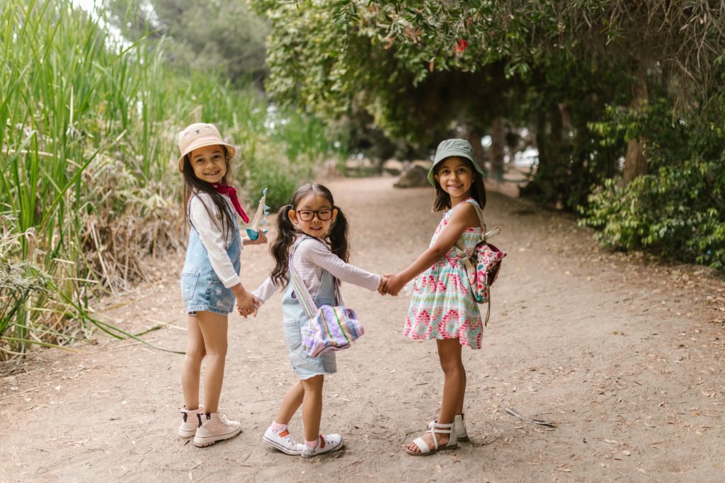 3 girls holding hand walking outside