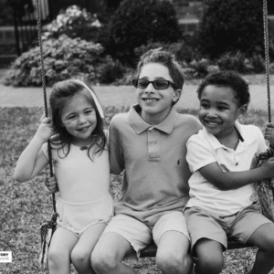 three kids sit in a swing