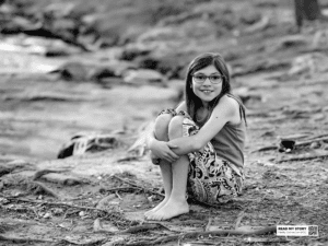 Chica sentada en la orilla de un río