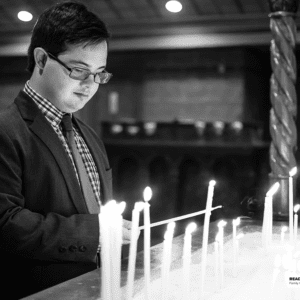 young man lights candles at church