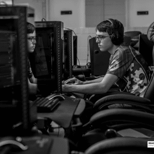 young man sits with headset on at a gaming pc