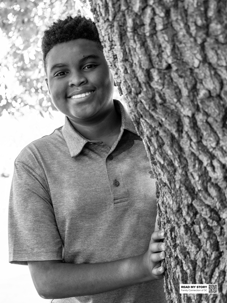 boy stands behind a tree