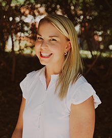 woman with blond hair in white dress smiling outdoors