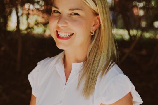 blond woman in white dress smiling outside