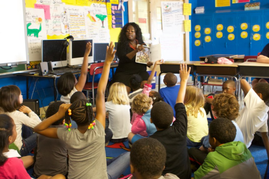 teacher reads to a group of students