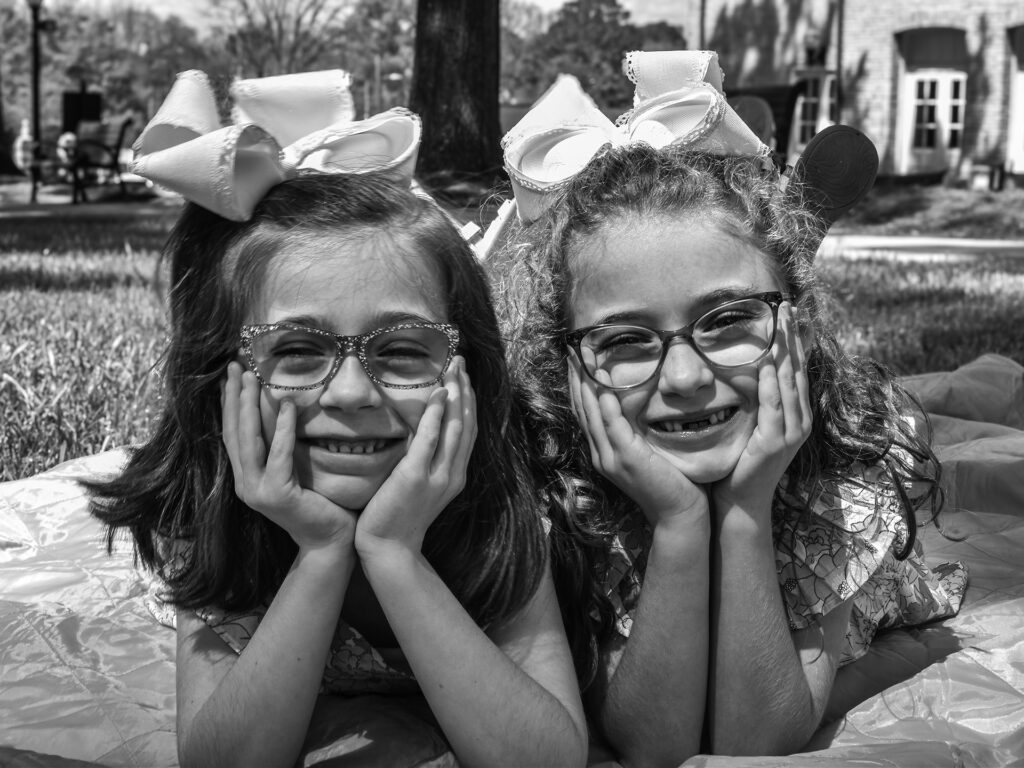 two girls lay on a blanket outside