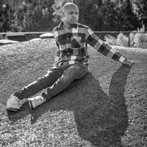 young man sits on a hill in the sunlight