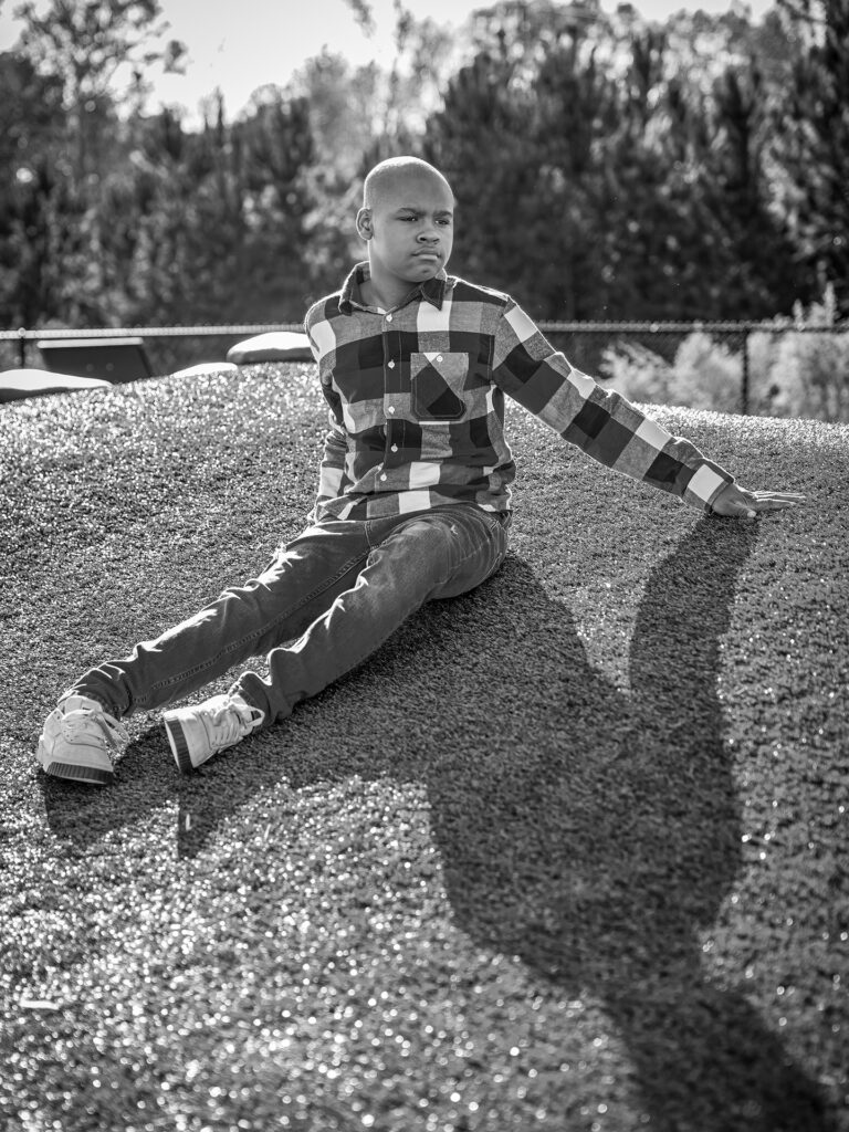 young man sits on a hill in the sunlight