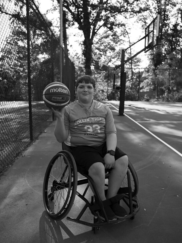un niño en silla de ruedas sostiene una pelota de baloncesto