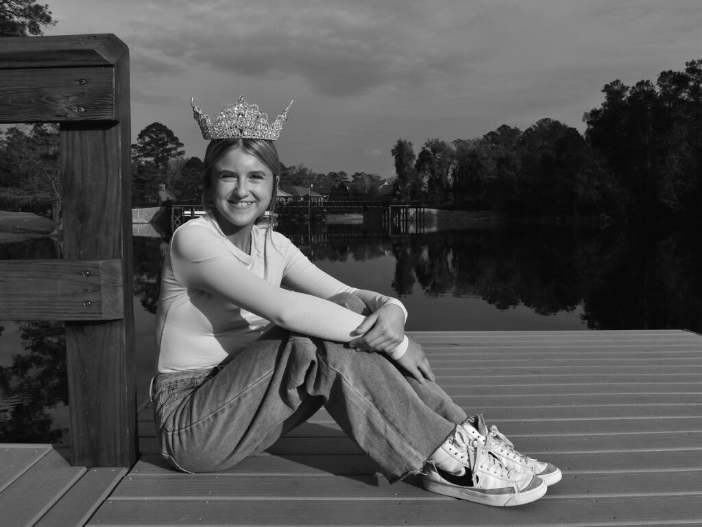 young woman in a tiara sits by the water