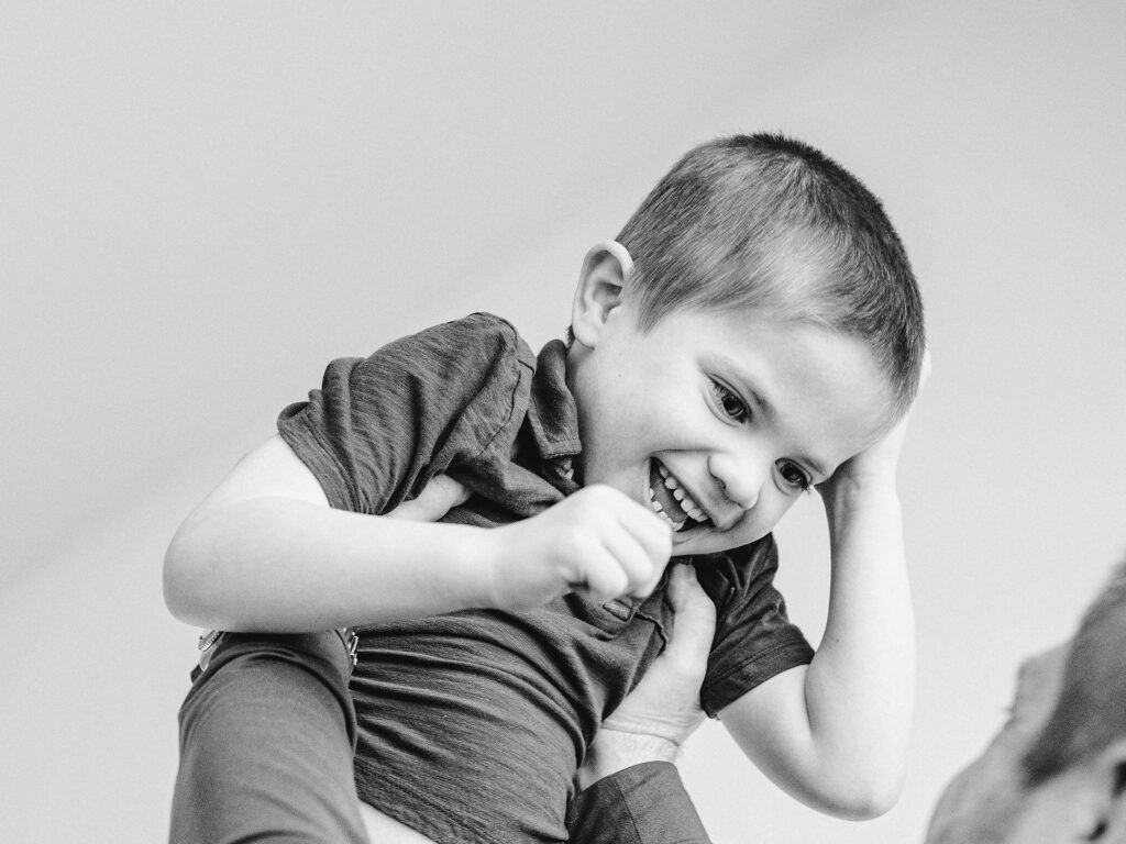 boy smiles being held overhead