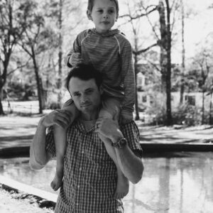 young boy rides on dad's shoulders