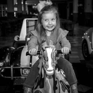young girl rides a hobbyhorse at the mall