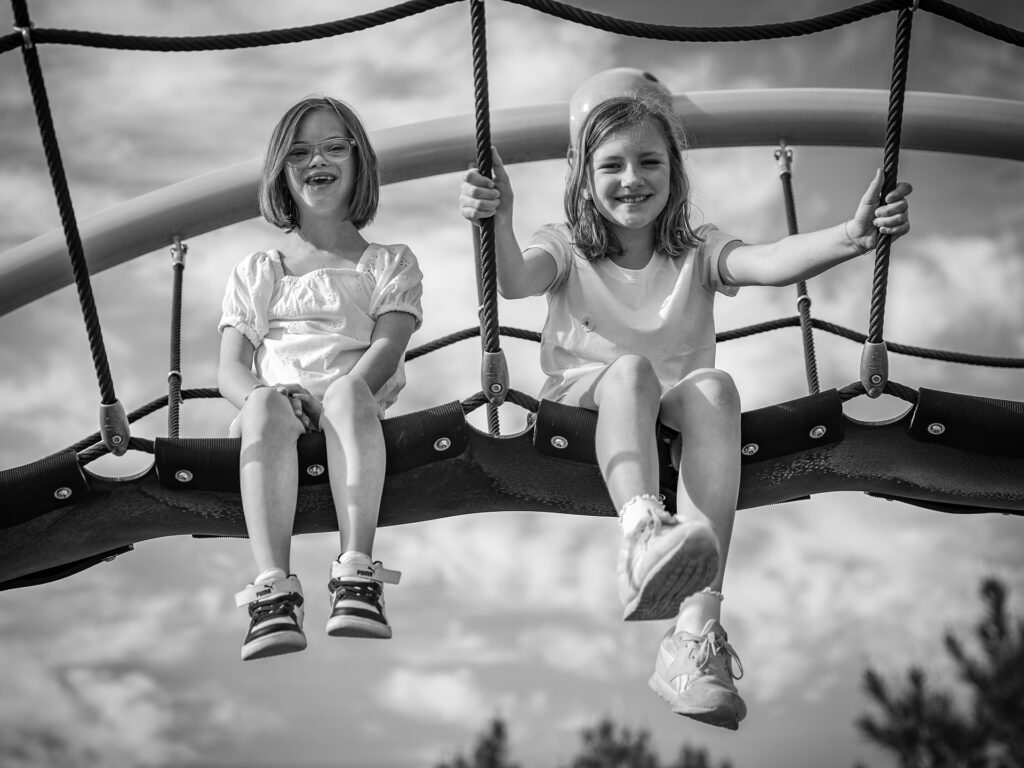 two girls sit on a rope bridge