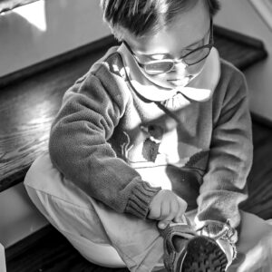young boy ties his shoes