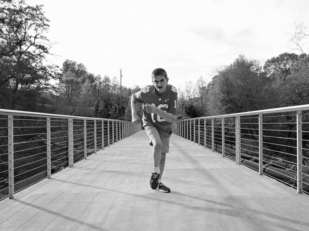 young man in football jersey runs down a bridge