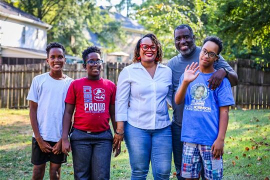 family stands smiling in the back yard