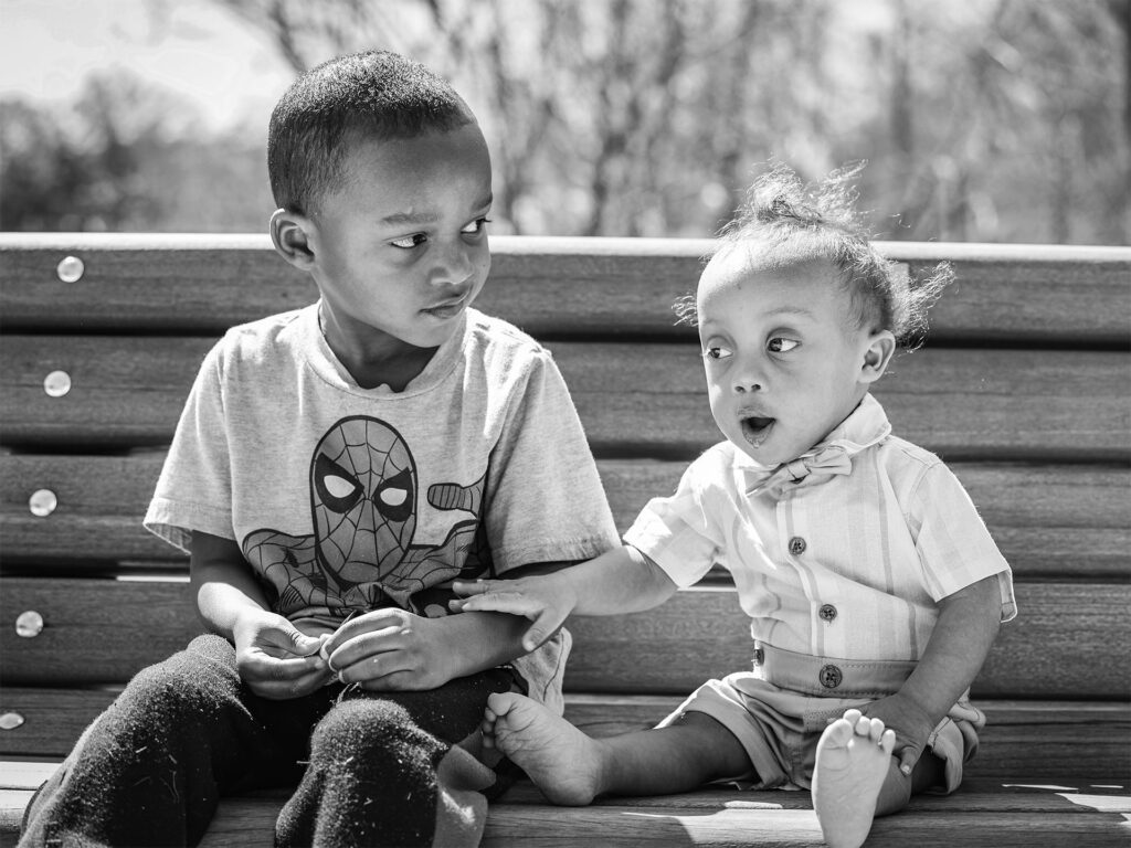 dos niños se sientan juntos en un banco del parque