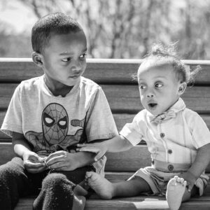 dos niños se sientan juntos en un banco del parque