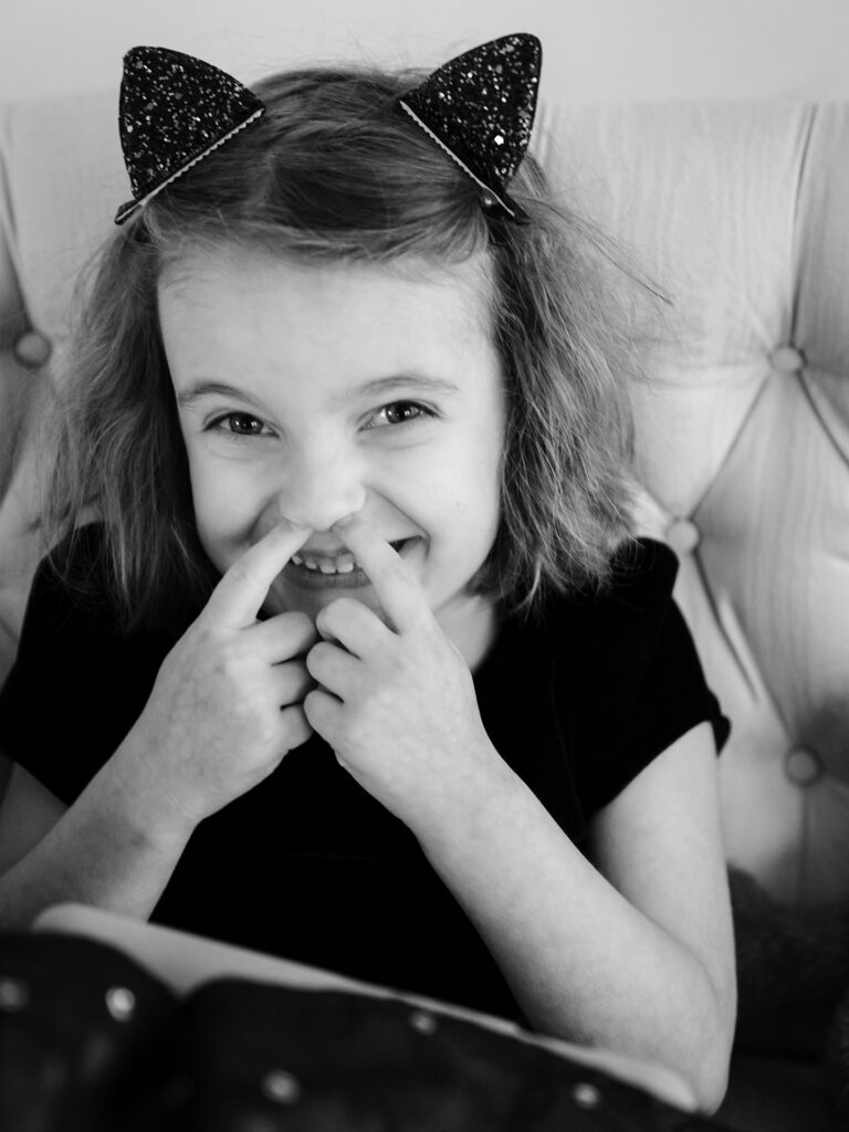 girl giggles with fingers in her nose