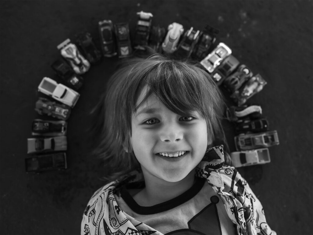 niño con coches de juguete dispuestos alrededor de su cabeza.