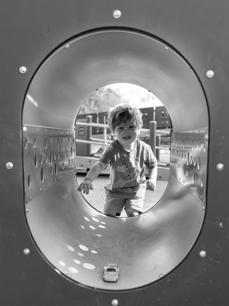 young boy climbs through a tunnel