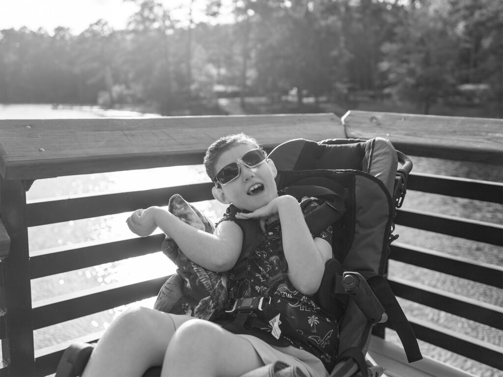 young man in a chair sits by a lake
