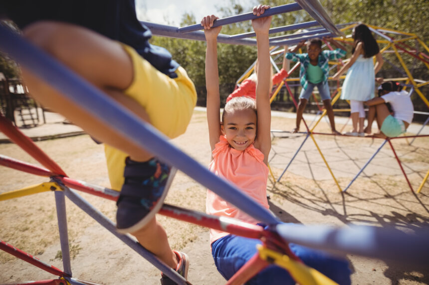 portrait-of-happy-girl-playing-on-monkey-bar